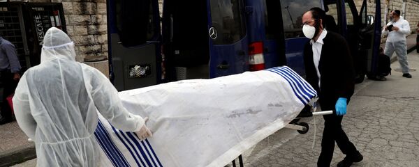 عمال جمعية الدفن اليهودية يرتدون ملابس واقية أثناء حملهم جثة ضحية لمرض فيروس كورونا لدفنه في القدس - سبوتنيك عربي