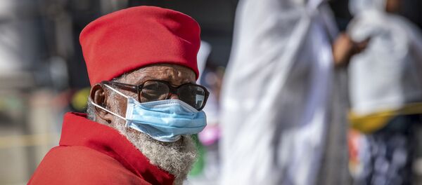 كاهن يرتدي قناعًا للحد من خطر الإصابة بفيروس كورونا الجديد وهو يحضر قداسًا صباح الأحد في كاتدرائية بولي مدهان عالم الإثيوبية الأرثوذكسية في أديس أبابا  - سبوتنيك عربي