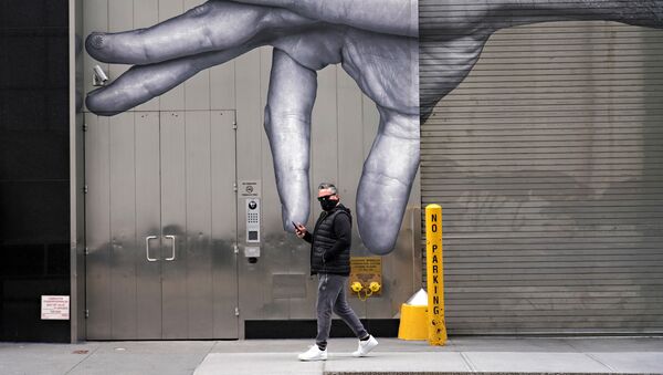 رجل يرتدي قناعاً واقياً يسير بجوار فن الشارع وسط انتشار الجائحة، فيروس كورونا في مدينة نيويورك، 05 أبريل 2020 - سبوتنيك عربي
