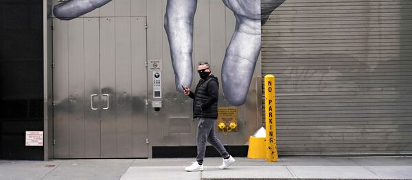 رجل يرتدي قناعاً واقياً يسير بجوار فن الشارع وسط انتشار الجائحة، فيروس كورونا في مدينة نيويورك، 5 أبريل 2020 - سبوتنيك عربي