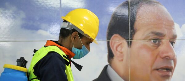 أحد أعضاء الفريق الطبي بجانب لافتة للرئيس المصري عبد الفتاح السيسي أثناء قيامه برش مطهر في محطة مترو الشهداء بالقاهرة كورونا - مصر  - سبوتنيك عربي