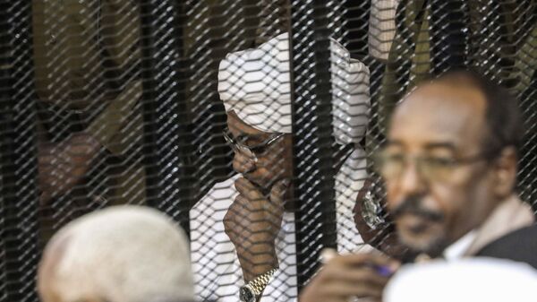 الرئيس السوداني السابق عمر البشير في قفص أثناء محاكمته بتهم الفساد وغسيل الأموال في الخرطوم - سبوتنيك عربي