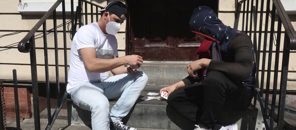 رجلان يرتديان أقنعة واقية يلعبان الورق أمام المنزل في بروكلين، نيويورك  2أبريل 2020 - سبوتنيك عربي