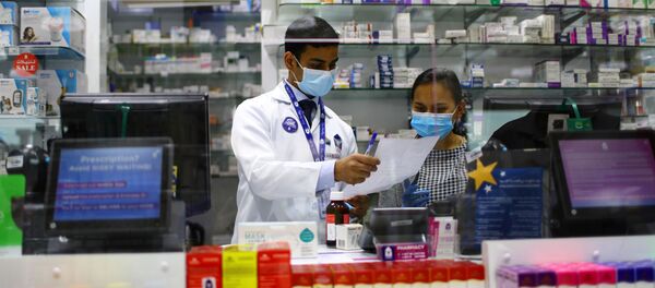 صيادلة خلف منضدة مغطاة بالزجاج خلال فترة الإغلاق على مدار 24 ساعة لمواجهة تفشي فيروس كورونا في دبي بالإمارات العربية المتحدة - سبوتنيك عربي