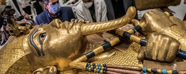  علماء آثار مصريون يرتدون الكمامات الحماية  من عدوى كورونا، خلال ترميم التابوت الذهبي للفرعون توت عنخ آمون (الذي حكم بين 1342 إلى 1325 ق.م.) في معمل الترميم بالمتحف المصري الكبير، الذي شيد حديثا في الجيزة بضواحي  القاهرة ، 13 أبريل 2020. - سبوتنيك عربي