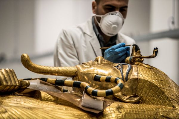  علماء آثار مصريون يرتدون الكمامات الحماية  من عدوى كورونا، خلال ترميم التابوت الذهبي للفرعون توت عنخ آمون (الذي حكم بين 1342 إلى 1325 ق.م.) في معمل الترميم بالمتحف المصري الكبير، الذي شيد حديثا في الجيزة بضواحي  القاهرة ، 13 أبريل 2020. - سبوتنيك عربي