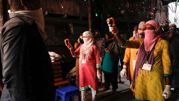 فحص كورونا في أحد أكبر الأحياء الفقيرة في آسيا باستخدام مقياس حرارة بالأشعة تحت الحمراء كإجراء وقائي ضد انتشار مرض فيروس كورونا في مومباي في الهند  - سبوتنيك عربي