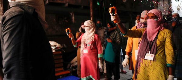 فحص كورونا في أحد أكبر الأحياء الفقيرة في آسيا باستخدام مقياس حرارة بالأشعة تحت الحمراء كإجراء وقائي ضد انتشار مرض فيروس كورونا في مومباي في الهند  - سبوتنيك عربي