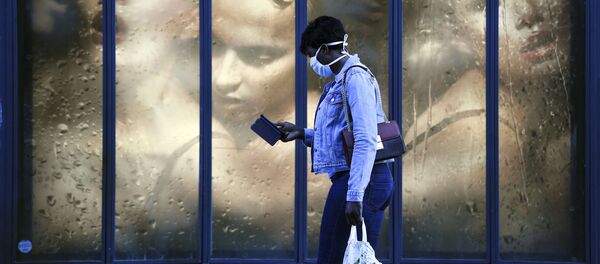 امرأة ترتدي كمامة طبية تمر بجوار نافذة متجر في باريس في 14 أبريل 2020، في اليوم التاسع والعشرين من الحجر الصحي المعلن في فرنسا، في إطار الاجراءات الوقائية لمنع انتشار فيروس كورونا (اوفيد-19). - سبوتنيك عربي