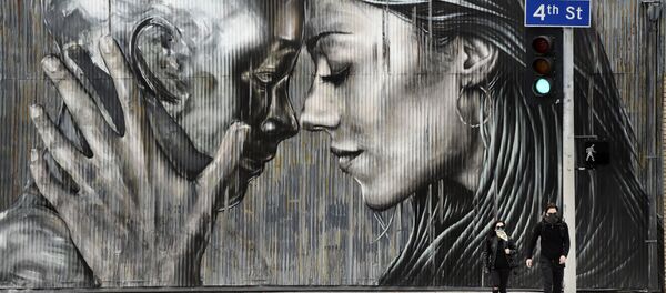 أشخاص يرتدون الكمامات وهم يعبرون الشارع أمام جدارية في حي الفنون في لوس أنجلوس، حيث تستمر أوامر البقاء في المنزل في كاليفورنيا بسبب الفيروس التاجي كورونا، 10 أبريل 2020. - سبوتنيك عربي