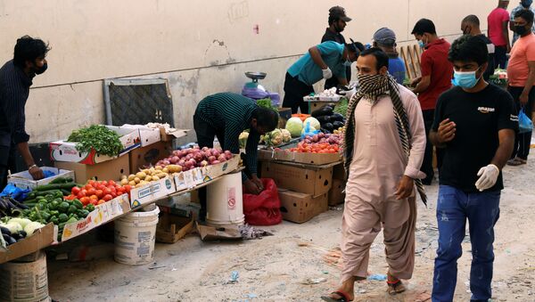 عمال أجانب يرتدون أقنعة واقية واقية يمشون في أحد شوارع السوق بعد تفشي مرض فيروس كورونا (COVID-19) في منطقة القوز الصناعية في دبي - سبوتنيك عربي