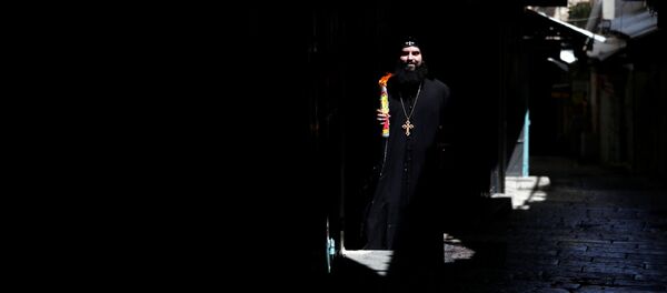 رجل دين مسيحي أرثوذكسي يحمل شموع العصا بعد احتفال النار المقدسة خارج كنيسة القيامة في البلدة القديمة في القدس وسط تفشي فيروس كورونا المستجد - سبوتنيك عربي