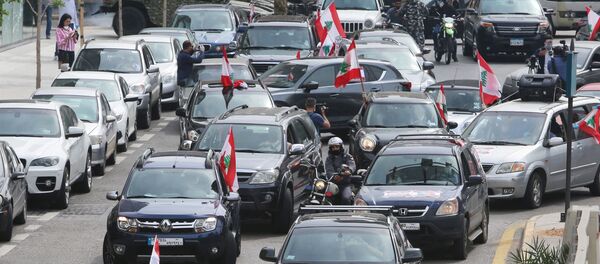 متظاهرون مناهضون للحكومة يحملون أعلاماً لبنانية وهم يحتجون في سياراتهم خلال إغلاق البلاد لمكافحة انتشار فيروس كورونا (COVID-19) في بيروت - سبوتنيك عربي