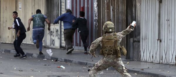 جندي من الجيش اللبناني يلقي عبوة غاز مسيل للدموع على متظاهرين مناهضين للحكومة في مدينة طرابلس - سبوتنيك عربي
