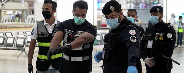 أفراد الشرطة والطيران المدني يرتدون أقنعة واقية في مطار الكويت مع استمرار عملية إعادة المواطنين الكويتيين إلى وطنهم - سبوتنيك عربي
