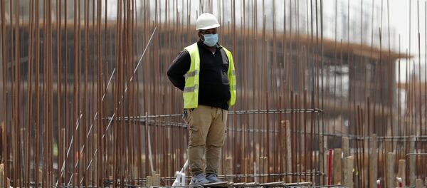 عامل يرتدي قناع وجه واقٍ يقف على مبنى قيد الإنشاء في العاصمة الإدارية الجديدة وسط مخاوف من انتشار مرض فيروس كورونا في مصر - سبوتنيك عربي