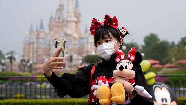 زائرة صينية ترتدي كمامة طبية وتلتقط صورة سيلفي في يوم إعادة افتتاح مدينة ديزني لاند في شنغهاي، الصين، 11 مايو/ أيار 2020 - سبوتنيك عربي