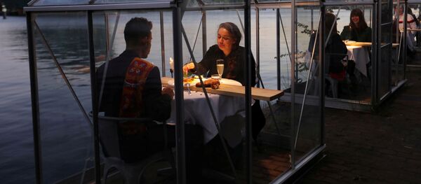 عارضات يقدمن نموذجا للزبائن وأفراد أسرة في مطعم، حيث يقام تجربة خدمة تقديم الأطباق والمشروبات إلى الأفراد في الدفئية الصحية، في إطار الإجراءات الوقائية  الآمنة بعد الخروج من الحجر الصحي بالتدريج، يستطيع فيه الضيوف تناول الطعام في أمستردام، هولندا، 5 مايو/ أيار 2020. - سبوتنيك عربي