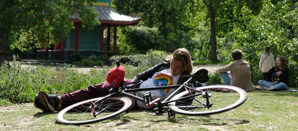 رجل يجلس بجوار دارجته في منتزه تحت أشعة الشمس في بريطانيا في ظل تفشي فيروس كورونا المستجد - سبوتنيك عربي