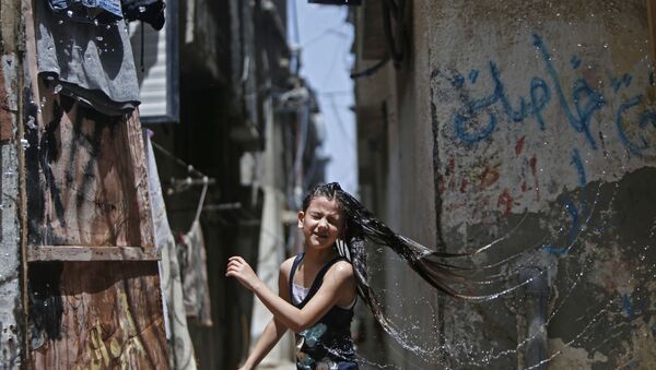 صبي يسكب الماء على رأسه طفلة لتخفيف الحر عنها، خلال موجة جو حار في مخيم البريج للاجئين وسط قطاع غزة، وسط جائحة  كوفيد-19 ، 19 مايو 2020. يذكر أن موجة حر شديد ضربت العديد من دول منطقة الشرق الأوسط. - سبوتنيك عربي