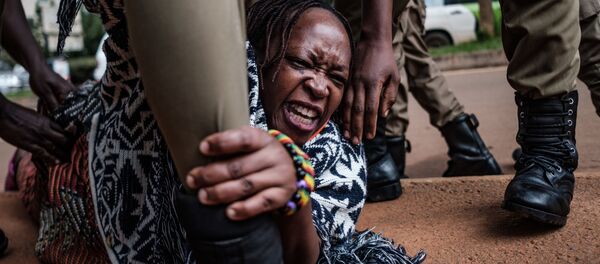 ستيلا نيانزي (في الوسط)  ناشطة أوغندية بارزة وناقدة للحكومة، يعتقلها ضباط الشرطة لأنها نظمت احتجاجا للمطالبة بتوزيع المزيد من المواد الغذائية من قبل الحكومة على الأشخاص الذين يكافحون ماليا بسبب الإغلاق على الصعيد الوطني المفروض للحد من انتشار  فيروس كورونا في كمبالا، 18 مايو 2020. - سبوتنيك عربي