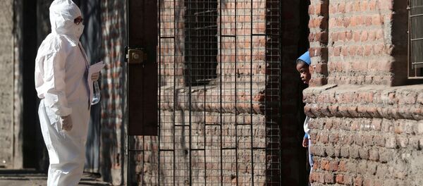 امرأة ترتدي بدلة واقية تتحدث إلى طفل في حي للمهاجرين، أثناء بدء الحجر الصحي العام، بسبب الأعداد المتزايدة من حالات الإصابة بفيروس كورونا في مدينة سانتياغو، تشيلي 16 مايو 2020. - سبوتنيك عربي