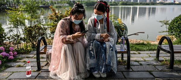 شابات يرتدين كمامات وأزياء تقليدية ةيجلسن على مقعد في حديقة بجوار بحيرة في مدينة ووهان، في مقاطعة هوبي بوسط الصين في 17 مايو 2020. - السلطات في منطقة بؤرة الجائحة  في ووهان  أمرت بإجراء اختبار كوفيد-19 الشامل لجميع المقيمين، والبالغ عددهم 11 مليون نسمة، بعد ظهور موجة جديدة من الحالات المصابة بفيروس كورونا خلال عطلة نهاية الأسبوع الماضي. - سبوتنيك عربي