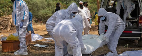 أقارب يحملون جثمان رجل توفي بسبب فيروس كورونا قبل دفنه في مقبرة في نيودلهي في الهند  - سبوتنيك عربي