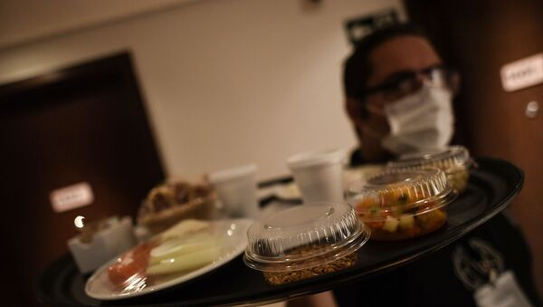 نادل مرتدي كمامة طبية يحضر الطعام في غرفة بفندق  - سبوتنيك عربي