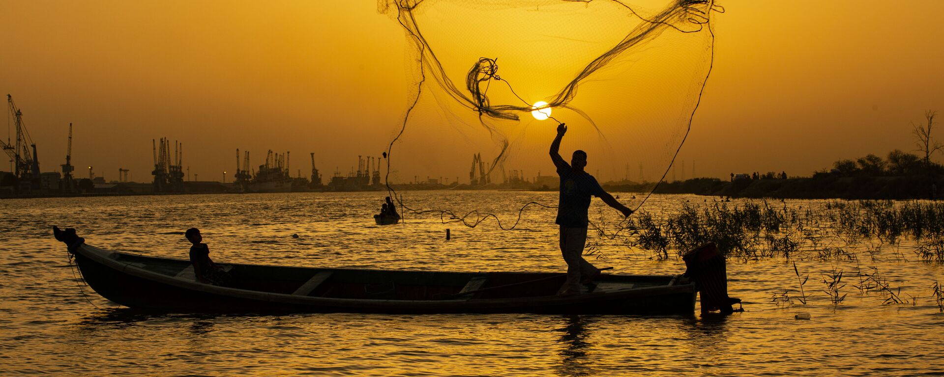 صياد السمك يلقي بشبكته عند الغروب في مياه نهر شط العرب في مدينة البصرة، العراق 12 يونيو 2020 - سبوتنيك عربي, 1920, 07.05.2022