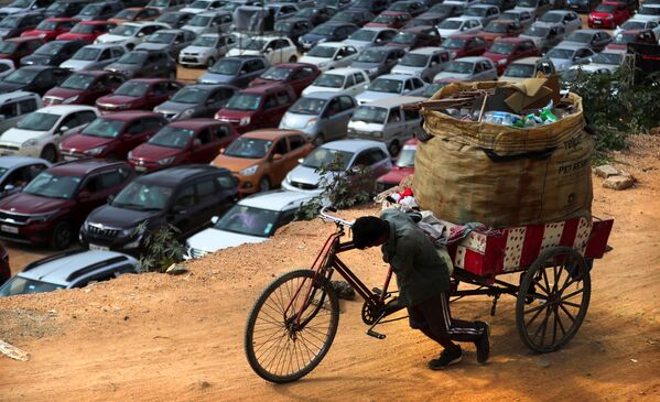 جامع القمامة والخردة يدفع بدراجته ذات الثلاث عجلات، بينما يجلس المسيحيون في سياراتهم الخاصة في إطار الحفاظ على التباعد الاجتماعي، خلال صلاة في كنيسة بيثال أ غ بنغالورو، الهند، الأحد 21 يونيو 2020. - سبوتنيك عربي