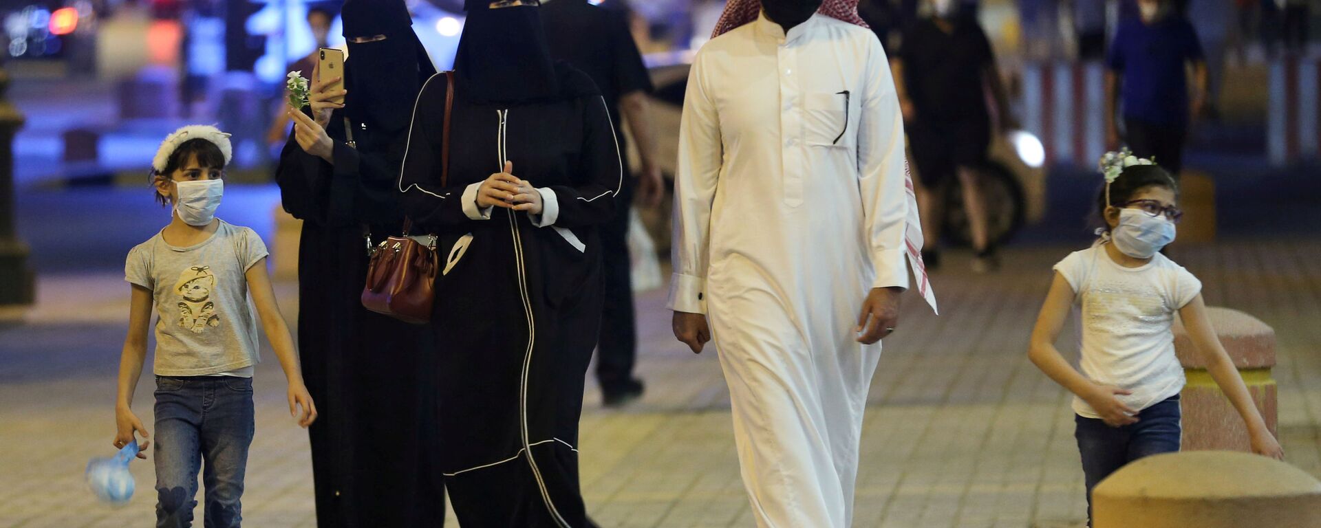 عائلة سعودية ترتدي أقنعة واقية للوجه تسير في شارع التحلية بعد أن خففت الحكومة قيود الإغلاق بعد تفشي مرض فيروس كورونا في الرياض - سبوتنيك عربي, 1920, 18.09.2021