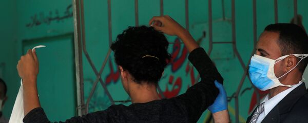 حارس مدرسة يفحص طالبا في الثانوية العامة قبل دخوله قاعة الامتحانات النهائية، وسط مخاوف من تفشي مرض كوفيد-19 في القاهرة، مصر، 21 يونيو 2020 - سبوتنيك عربي